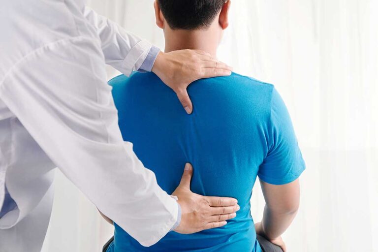 Clinician performing a gentle spinal adjustment while a patient lies comfortably on a treatment table.
