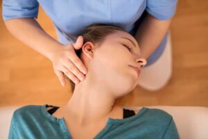 A person applying a cold pack to their lower back while sitting comfortably at home.