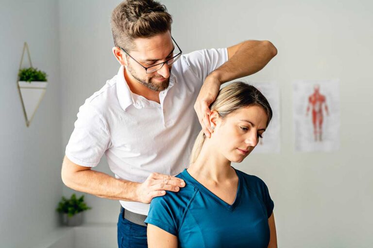 Person using their hand to massage a sore shoulder while seated indoors with a relaxed posture.