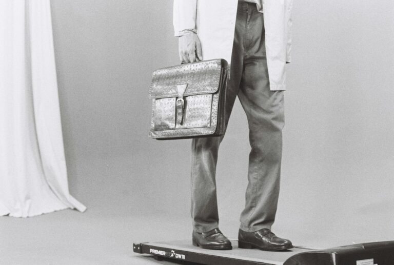 Adult practicing balance beside a sturdy chair while maintaining an upright, neutral posture.